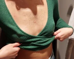 A student in the fitting room measures the tops on her small tits